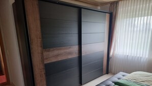Un dormitorio con cama, un armario grande y una ventana con cortinas.