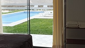 Een hotelkamer met een grote glazen schuifdeur die uitkomt op een zwembad, een bed en een kledingkast.