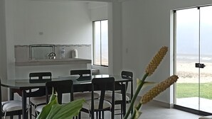 Een modern interieur met een eethoek, grote ramen en uitzicht op het strand.