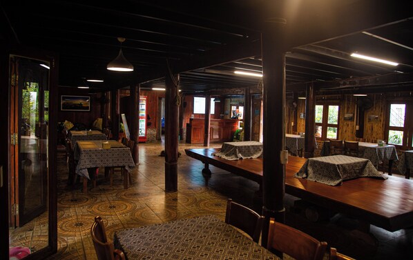 A restaurant with wooden interiors, tables with patterned tablecloths, and a tiled floor. - Green Sapa Homestay (Sa Pa)