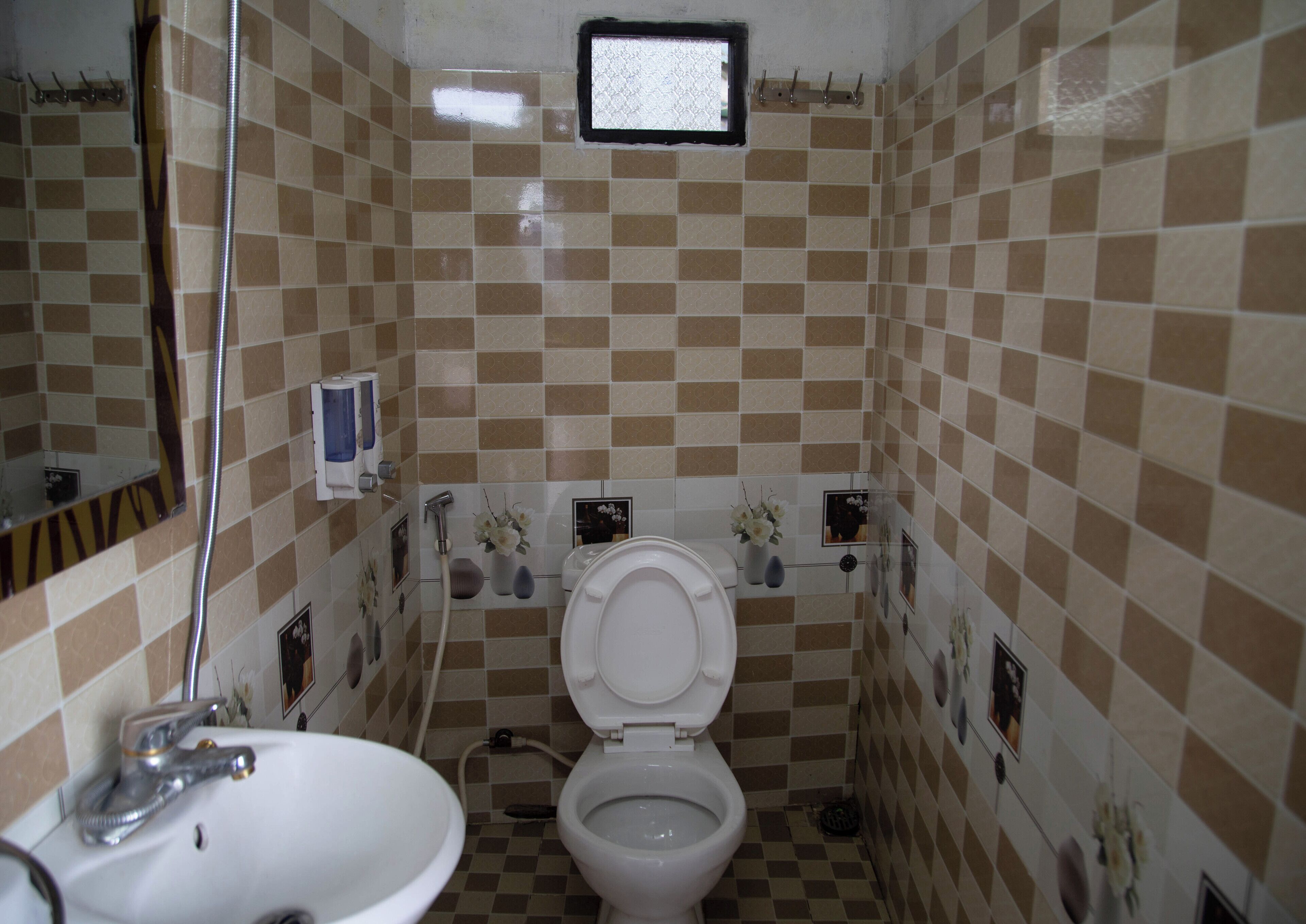 A bathroom with a checkered tile pattern, a white sink, a toilet, a shower, and a mirror.