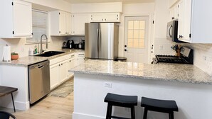 A modern kitchen with white cabinetry, a stainless steel refrigerator, granite countertops, and a built-in stove. - Pool House near Downtown Round Rock (Round Rock)