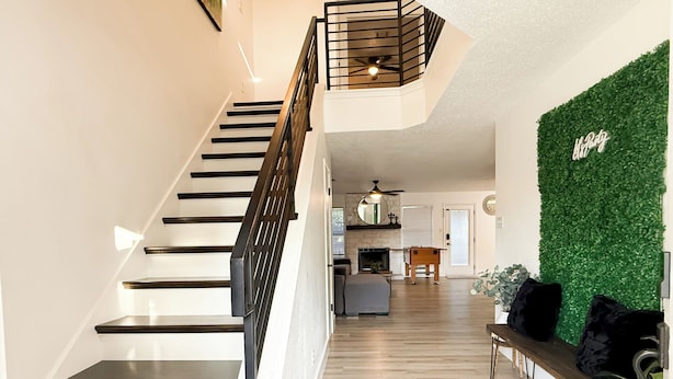A staircase with black railings leading to a living area with a green wall and a bench. - Pool House near Downtown Round Rock (Round Rock)