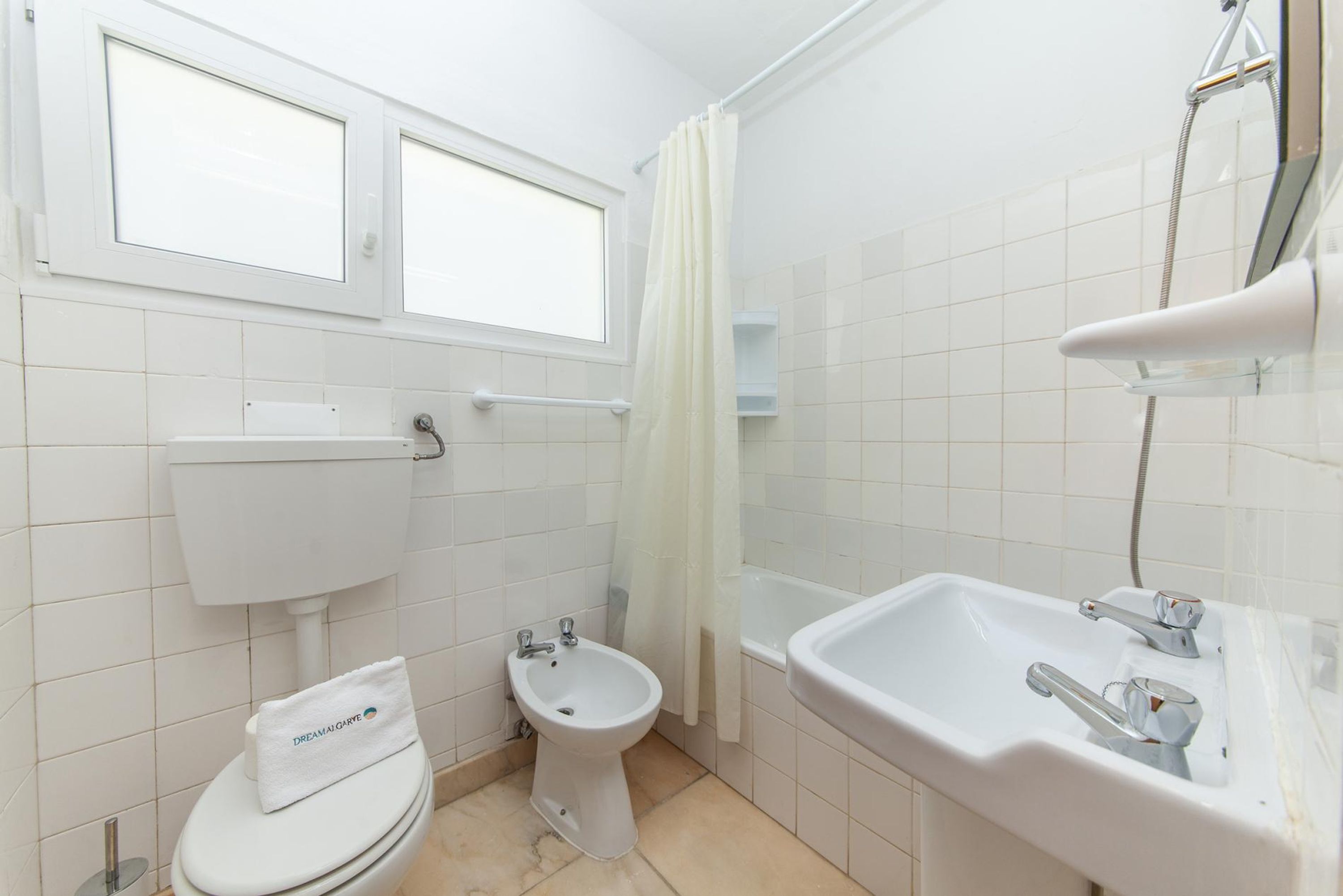 A bathroom with a toilet, bidet, bathtub, and sink.