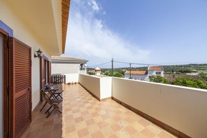 A balcony with a tiled floor, a table with chairs, and a view of the surrounding landscape. - A56 - Westway Rossio Holiday Place (Lagos)