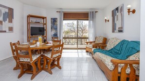 A living room with a dining table, chairs, a sofa, and a TV on a wooden stand. - B78 - Fragoso Downtown Apartment (Lagos)