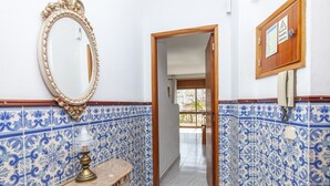A bathroom with blue and white patterned tiles, a marble sink, a decorative mirror, and a wooden door leading to another room. - B78 - Fragoso Downtown Apartment (Lagos)