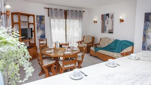 A dining area with a wooden table and chairs, a sofa, and a television on a wooden stand. - B78 - Fragoso Downtown Apartment (Lagos)