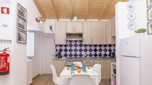 Une cuisine moderne avec des meubles blancs, un pare-feu en carreaux et un coin repas comprenant une table et des chaises blanches.