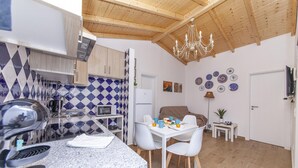Une cuisine moderne avec un plan de travail en granit, des chaises blanches et une table à manger pour quatre personnes.