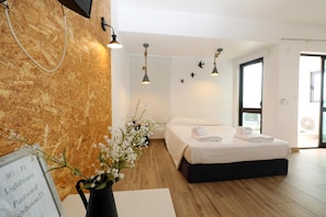 Ein modernes Hotelzimmer mit Holzboden, einem großen Bett mit weißer Bettwäsche, einer Vase mit Blumen und einem Schild, das WLAN und das Passwort anzeigt.