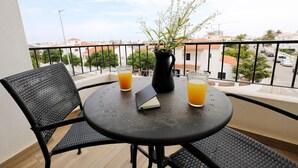 A balcony with a round table, two chairs, a potted plant, and two glasses of orange juice. - A57 - Lighthouse Apartment in Via Dona Ana Lagos (Lagos)