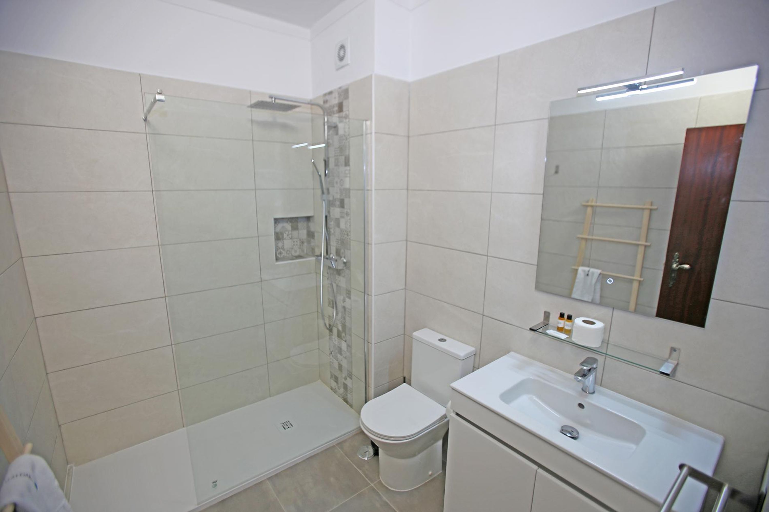 Une salle de bain moderne avec une douche à parois de verre, des toilettes, un lavabo et un miroir.