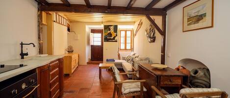 Una cocina rústica con armarios de madera, un lavamanos y una estufa. Hay un comedor con mesa y sillas de madera.