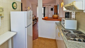 A kitchen with a refrigerator, microwave, stove, and a tiled backsplash. - B46 - Belavista Torraltinha Flat (Lagos)
