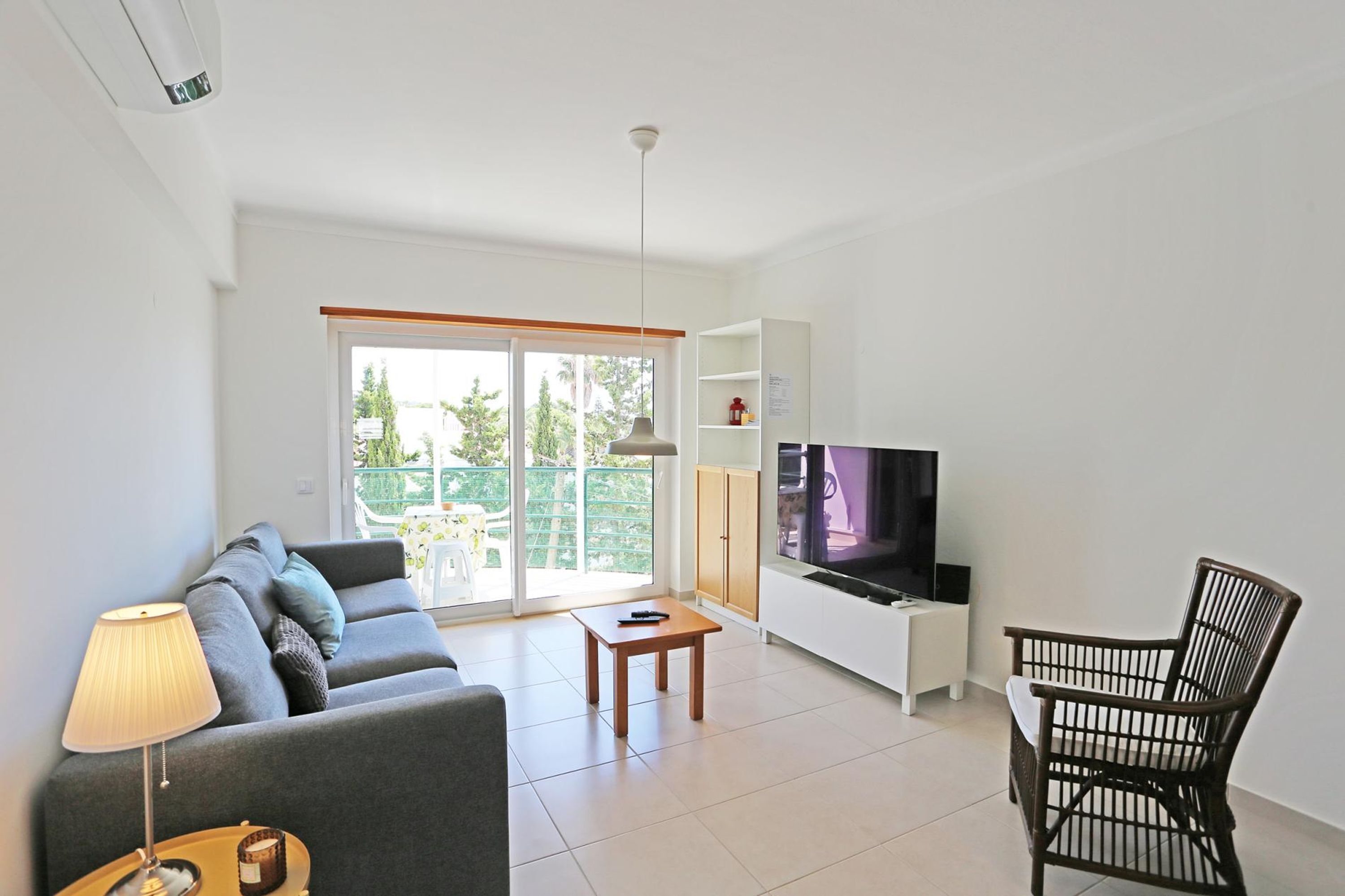 A living room with a sofa, a table, a TV, and a chair.