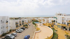 Zona residencial con edificios modernos, una piscina y una playa al fondo.