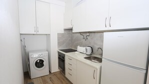 A compact kitchen with a washing machine, a toaster, and a refrigerator. - A09 - Sidestreet Mineiro Studio (Lagos)