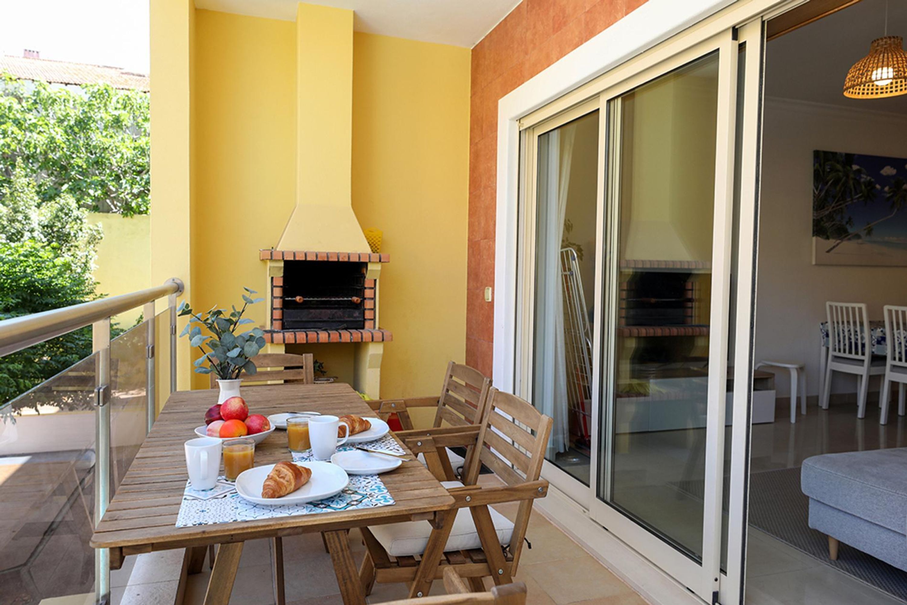 Ein Holztisch mit Frühstücksangeboten, ein Backofen und eine Glastür zu einem Balkon.