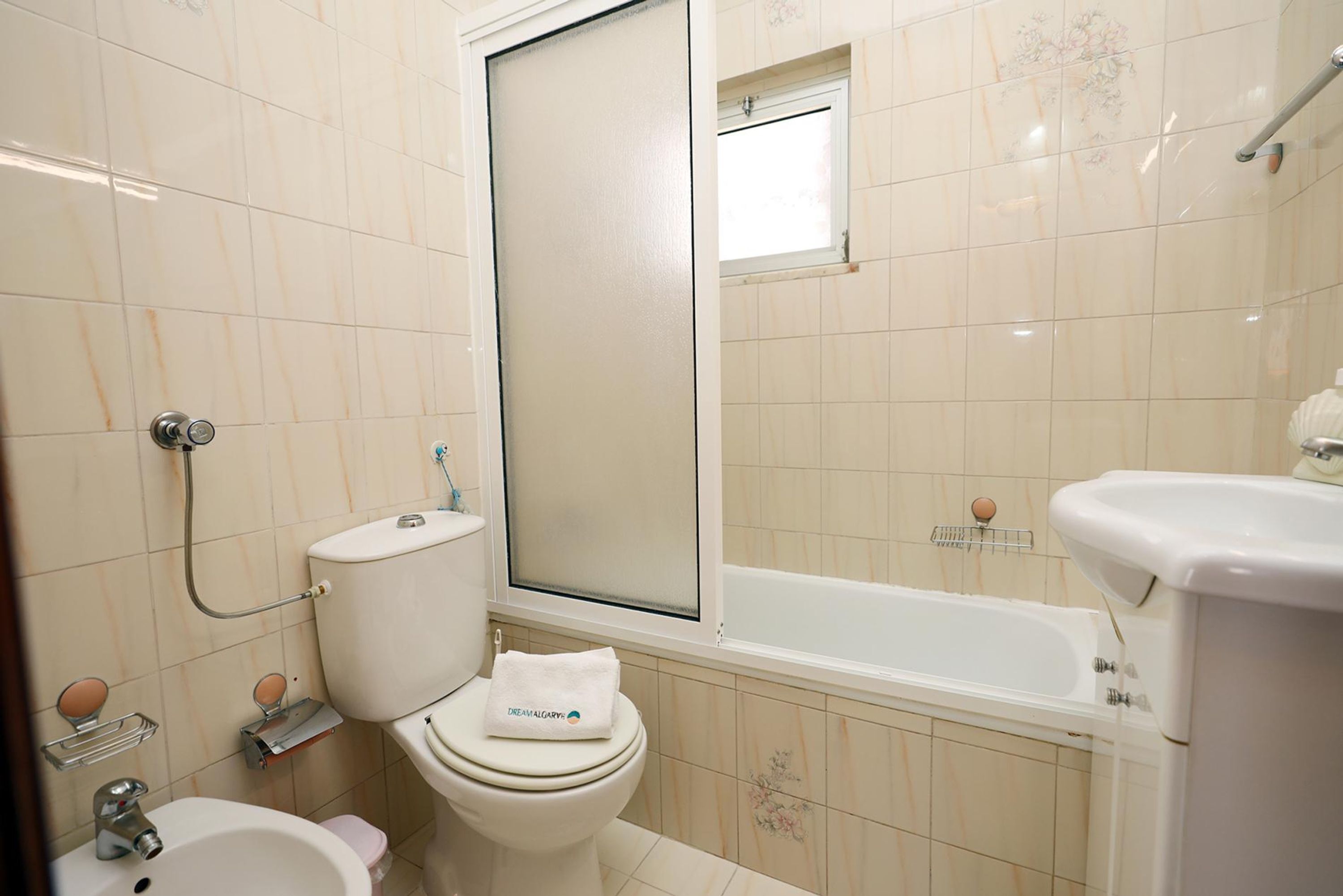 A bathroom with a toilet, bidet, sink, and bathtub.