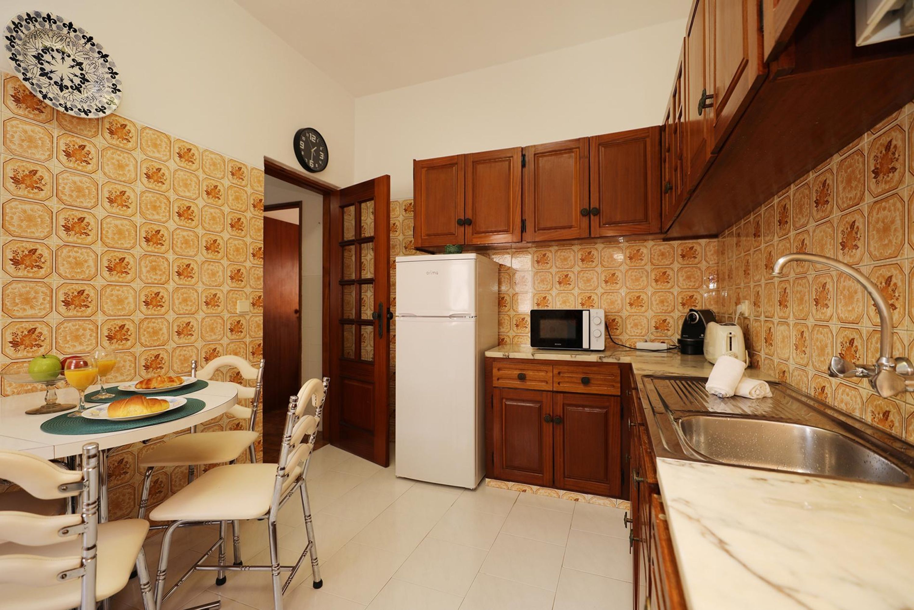 Cocina compacta con armarios de madera, un refrigerador, un microondas y un lavamanos.