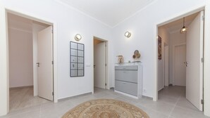 A modern interior with a central rug, a wall-mounted mirror, and a cabinet with drawers.