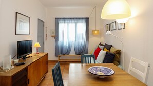 A modern living room with a wooden dining table, a television, and a lamp. - B94 - Casa dos Peixeiros in Lagos (Lagos)