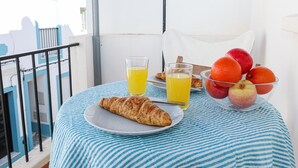 A balcony with a table set for breakfast, including croissants, orange juice, and a fruit bowl. - B94 - Casa dos Peixeiros in Lagos (Lagos)