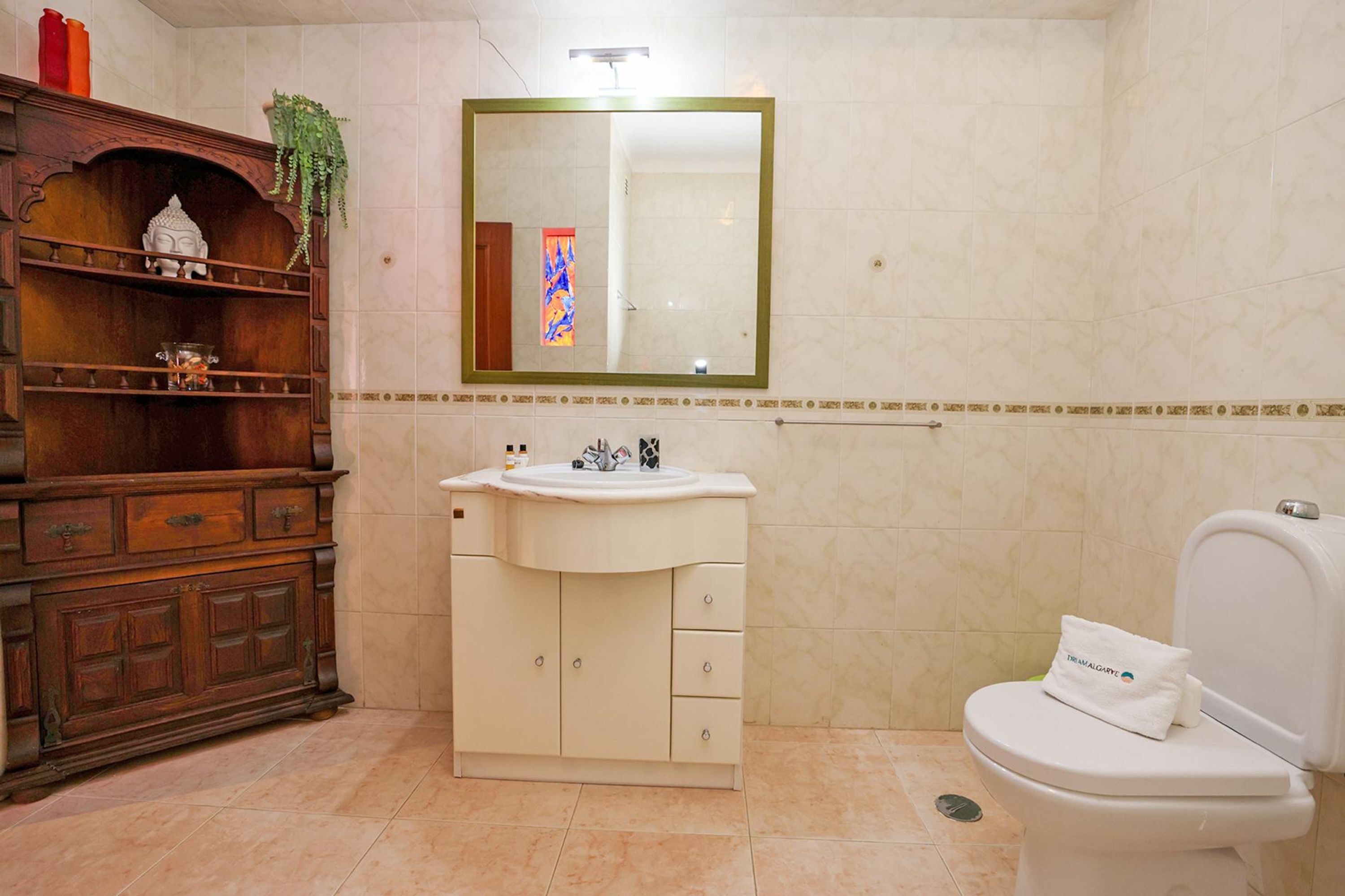 A bathroom with a wooden vanity, a sink, and a toilet.