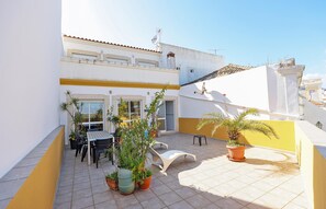 A courtyard with a dining area, potted plants, and a white lounge chair. - C25 - Town Center Apartment in Lagos (Lagos)