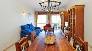 A dining area with a wooden table, blue sofa, and a chandelier. - C25 - Town Center Apartment in Lagos (Lagos)