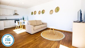 Eine moderne Wohnung mit Küche, einer Couch, einem Essbereich und einem Fernseher.