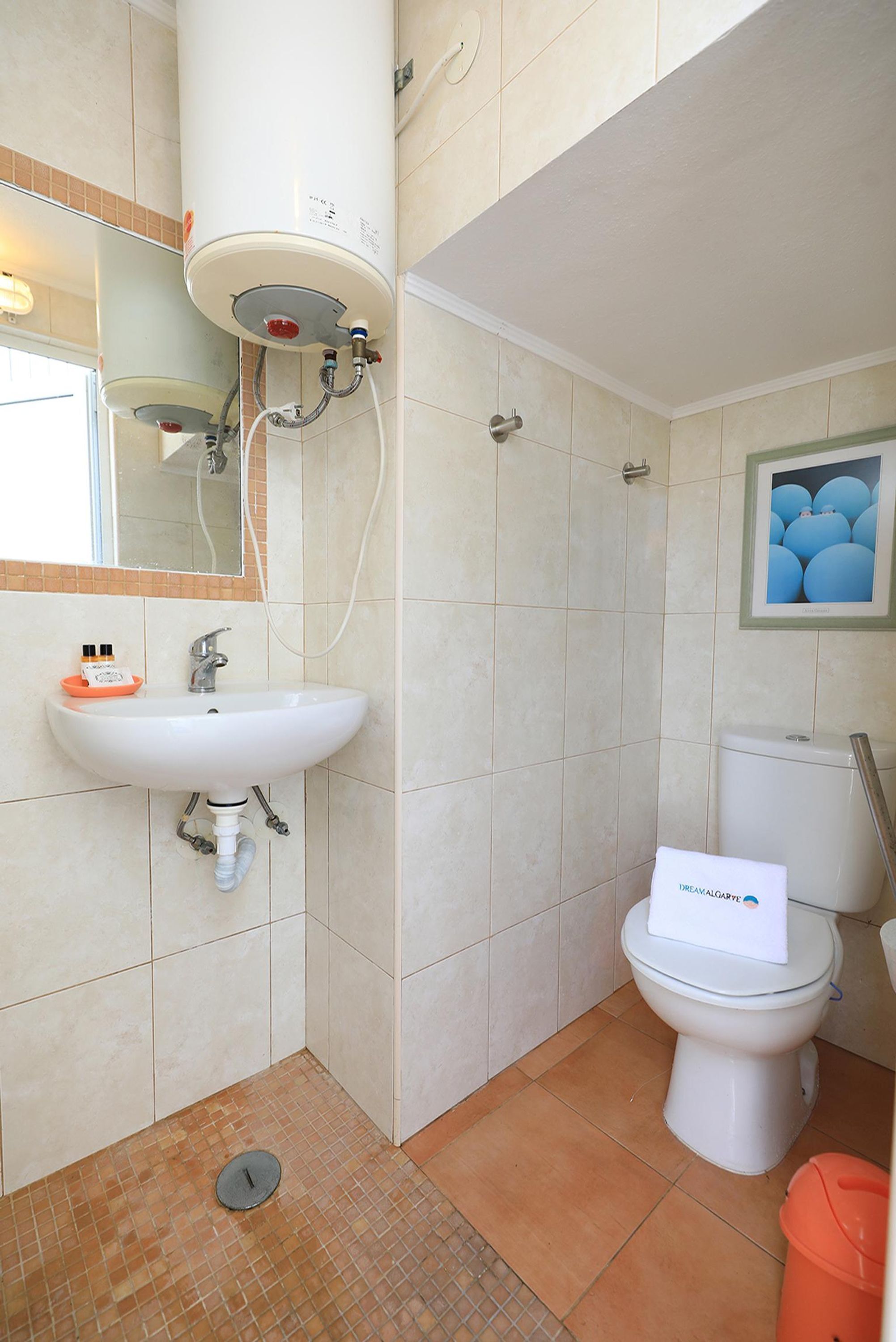 Une salle de bain équipée d’un lavabo, de toilettes et d’un chauffe-eau.