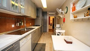 A modern kitchen with white cabinets, a brick backsplash, and a dining area with a table and basket.