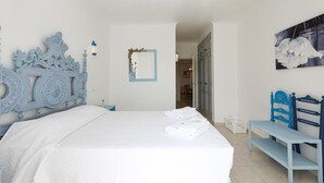 A bedroom with a large bed, a wooden headboard, a bedside table, a bench, a wall-mounted mirror, and a framed picture. - C13 - Ameijeira Holiday Apartment in Lagos (Lagos)