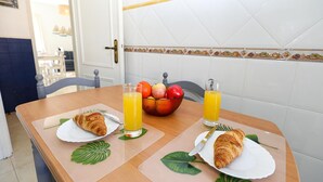 A breakfast table with croissants, a fruit bowl, and glasses of orange juice. - C13 - Ameijeira Holiday Apartment in Lagos (Lagos)