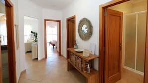 A hallway with a wooden console table, a mirror, and a door leading to a bathroom. - B95 - Casa Melo Apartment in Praia da Luz (Lagos)