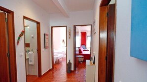 A hallway with wooden flooring leading to a bedroom with a red bedspread. - B86 - Beachline Apartment in Praia da Luz (Lagos)