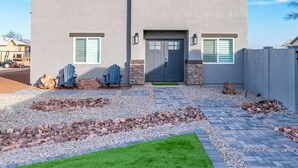 A modern two-story house with a flat roof, a front porch, and a well-maintained lawn. - 2-bedroom Home-casita , private backyard with grill, putting green,cornhole (Buckeye)