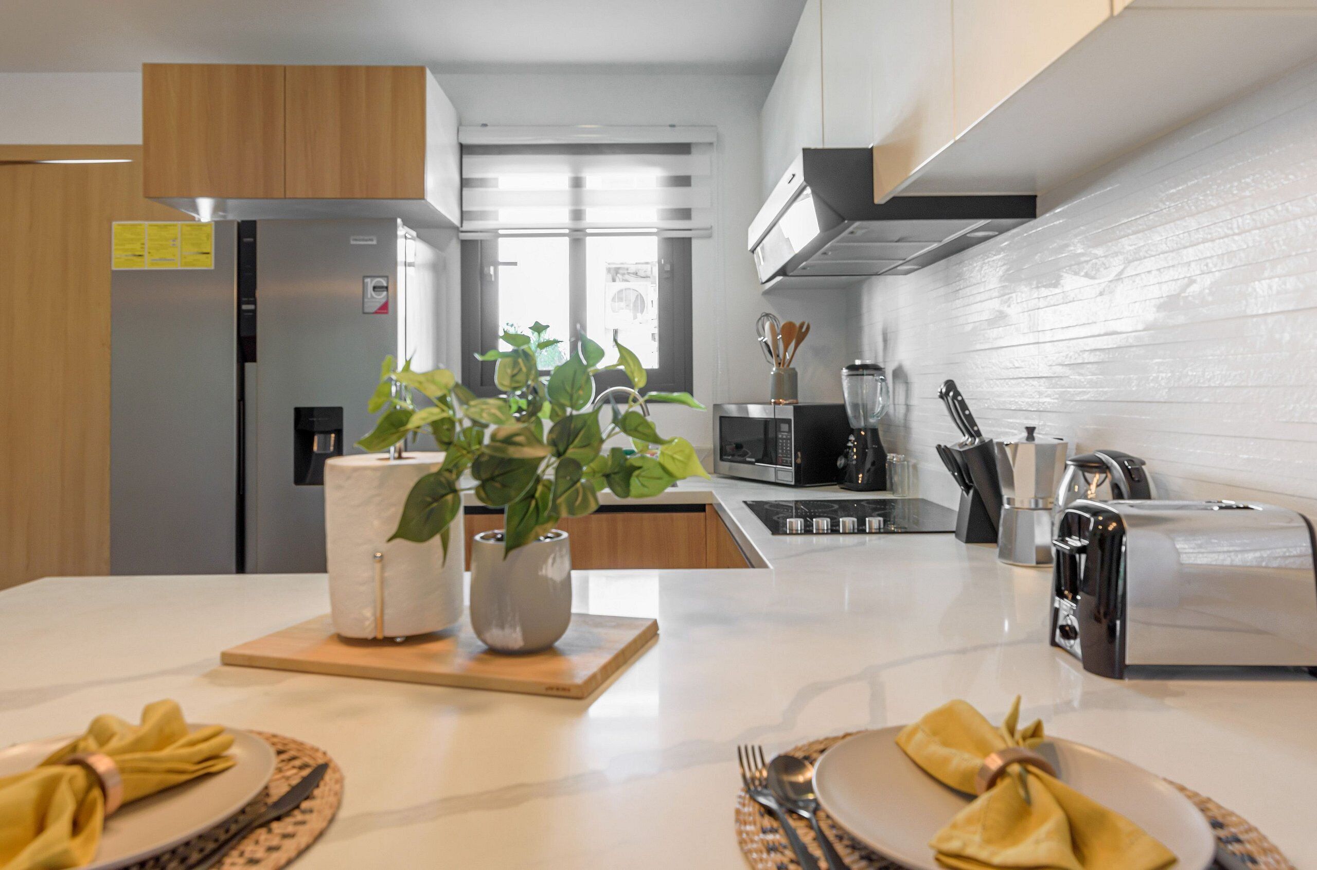 A modern kitchen with a built-in refrigerator, microwave, toaster, and a large window providing natural light.