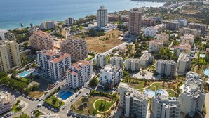 A coastal residential area with high-rise buildings, a swimming pool, and a view of the sea. - B97 - Flor da Rocha Apartment in Portim o (Portimão)