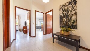 A hallway with a tiled floor, wooden doors, and a black bench with a plant. - B97 - Flor da Rocha Apartment in Portim o (Portimão)