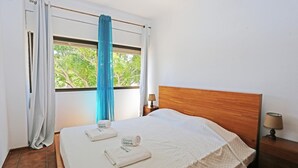 Une chambre d’hôtel avec un lit, une table de chevet, une lampe et une fenêtre avec des rideaux.