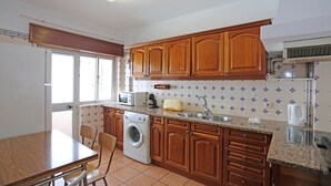 Une cuisine avec des meubles de rangement en bois, un lave-linge, un four à micro-ondes et un évier.