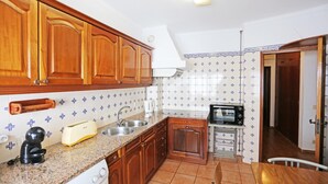 Une cuisine avec des meubles de rangement en bois, un grille-pain, un évier et un four à micro-ondes.