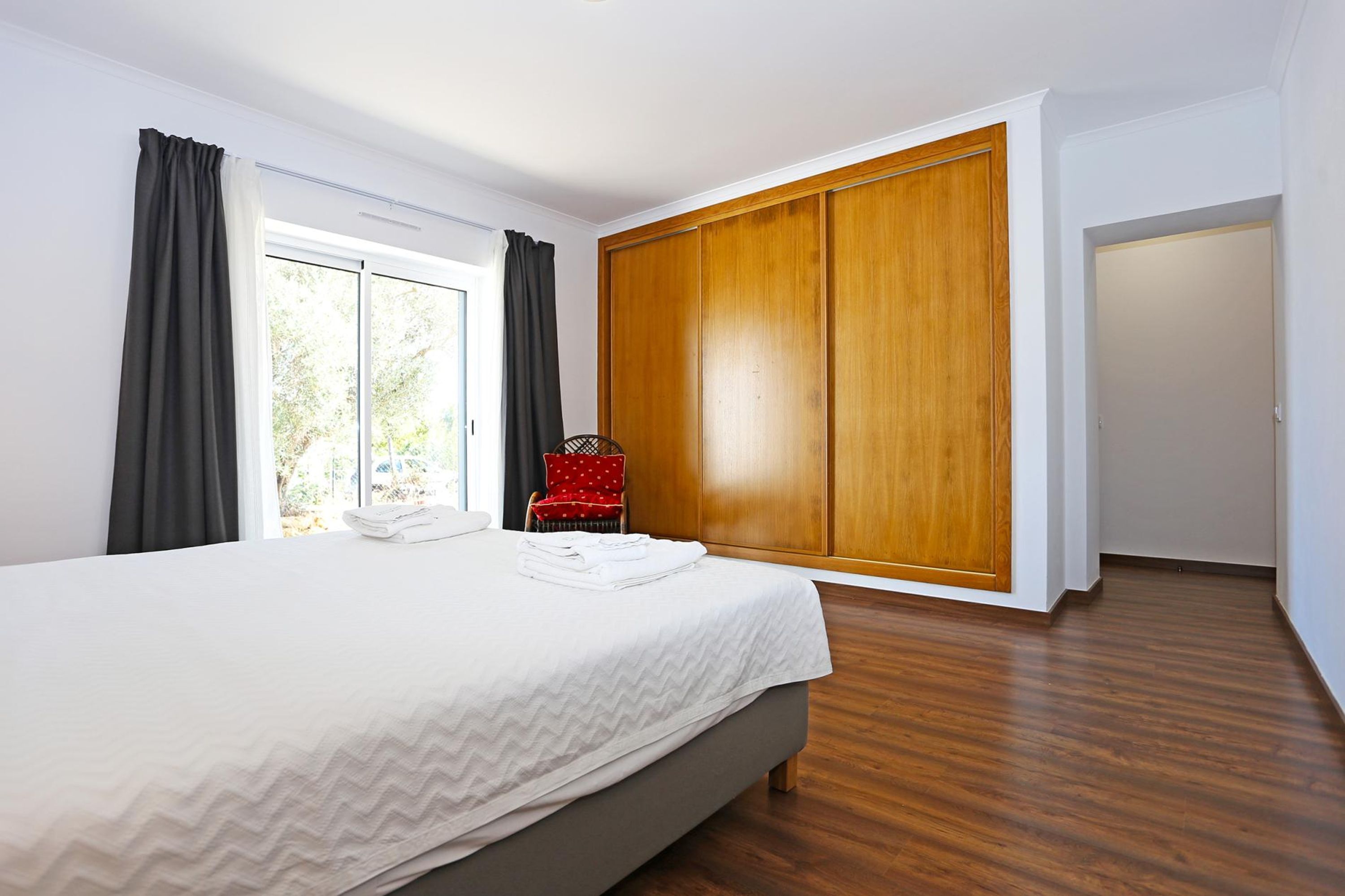 A bedroom with a large bed, a wardrobe, and a chair.