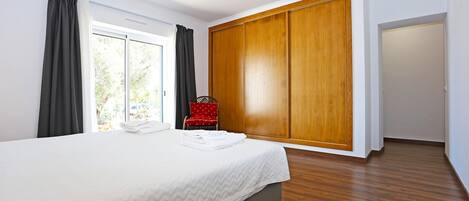 A bedroom with a large bed, a wardrobe, and a chair.