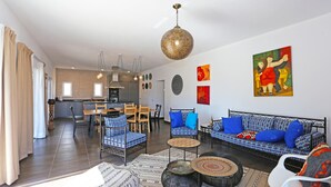 Una sala moderna con un conjunto de sofás, un comedor y una cocina al fondo.