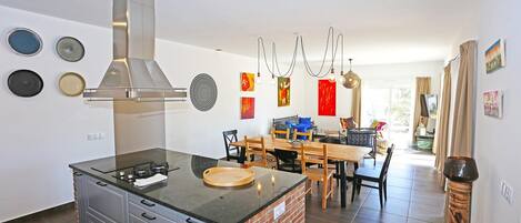 Una cocina moderna con una isla central, comedor con sillas y un ventanal grande.
