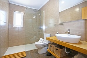 A modern bathroom with a shower, toilet, and sink.